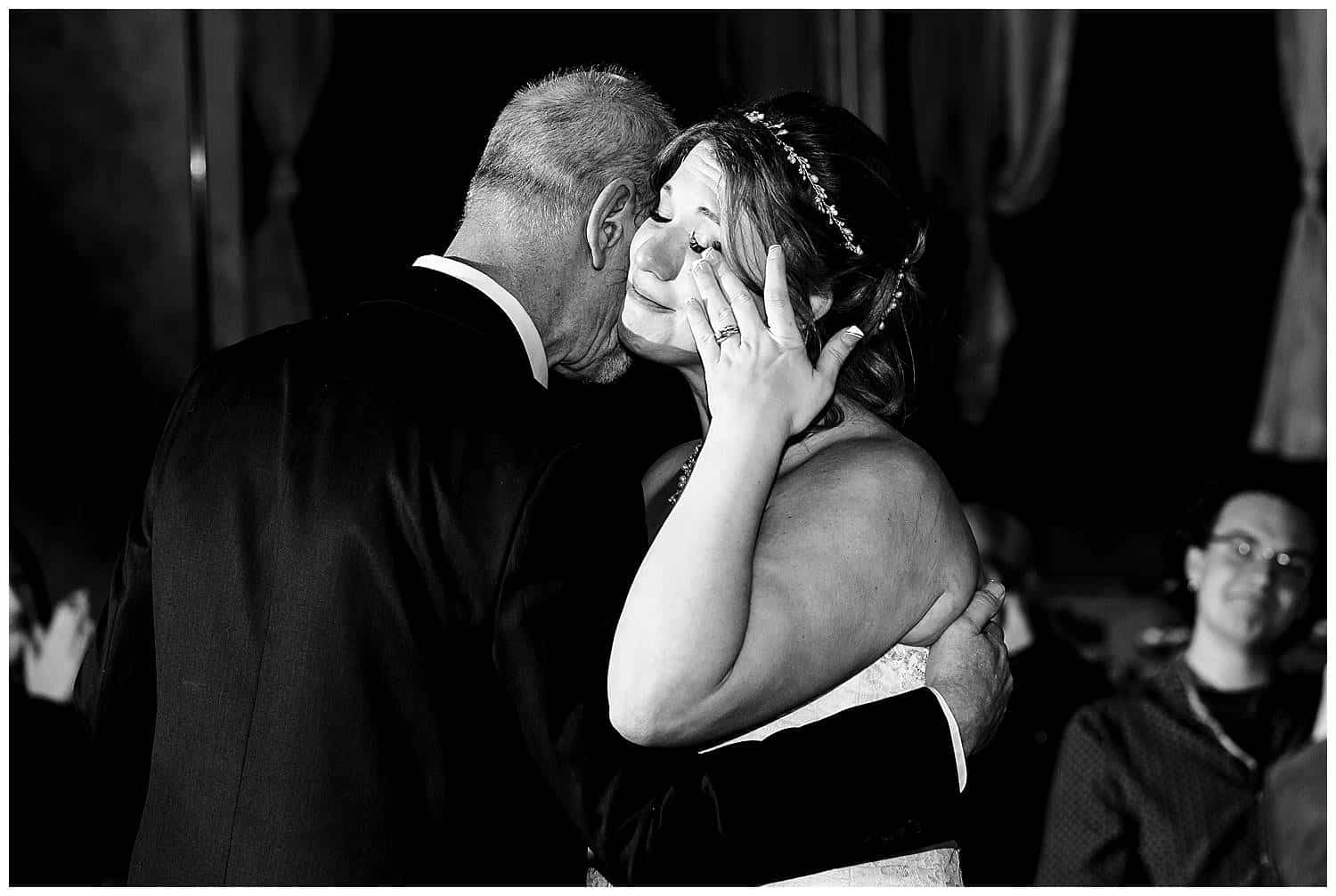 Bride wiping away tear while dancing with dad